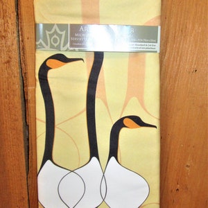 May include: A yellow kitchen towel featuring a design of three stylised geese in black, white and orange. The towel measures 70cm by 50cm and is absorbent and lint-free.