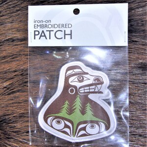 May include: An iron-on embroidered patch with a Native American-inspired design of a bear or wolf and a forest. The patch is brown, white, and green, and is in a clear plastic bag. The packaging reads "Iron-on EMBROIDERED PATCH".