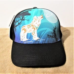 May include: A black baseball cap featuring a blue, green and white wolf howling at the moon graphic. The wolf is styled with tribal patterns.