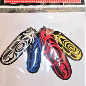 May include: Four embroidered patches in the shape of feathers. The feathers are in the colours of red, yellow, blue, and white. The feathers have a traditional design.