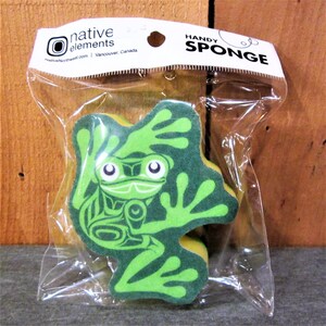 May include: A green frog-shaped sponge with a Native American design. The sponge is packaged in a clear plastic bag with a white header that reads "Native Elements" and "Handy Sponge".