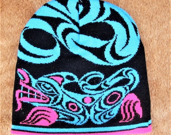 May include: Black knitted beanie with a blue and pink design featuring a stylised animal face. The design is reminiscent of Native American art.