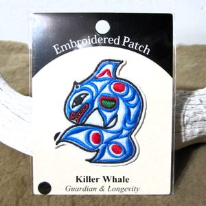Può includere: Toppa ricamata con un design stilizzato di un'orca blu e bianca con accenti rossi. La toppa è su uno sfondo bianco con le parole "Embroidered Patch" in alto e "Killer Whale Guardian & Longevity" in basso.