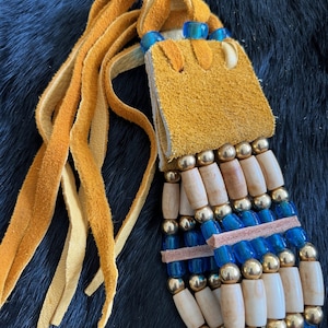 May include: A multi-strand necklace with brown leather tassels, blue glass beads, gold beads, and wooden beads.