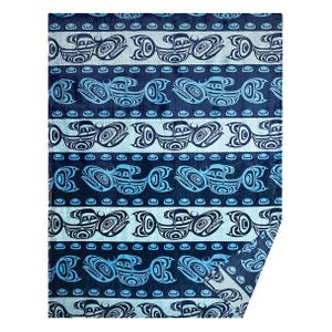 May include: A blue and white patterned blanket with a repeating design of stylized bird or fish shapes. The blanket features horizontal stripes with alternating patterns and colours, creating a visually appealing textile.