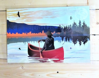 May include: A red canoe with a person paddling on a lake with a mountain range in the background. The sky is a mix of blue, orange, and pink.