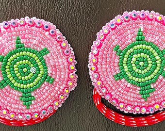 May include: Two pink beaded hair ties with green beaded turtle designs.