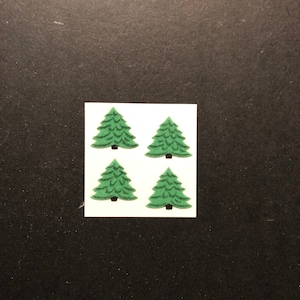 Könnte beinhalten: Vier grüne Filz-Weihnachtsbaum-Aufkleber auf weißem Hintergrund.
