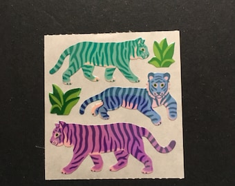 May include: Three colorful tiger stickers with green leaves. The tigers are teal, blue, and purple.