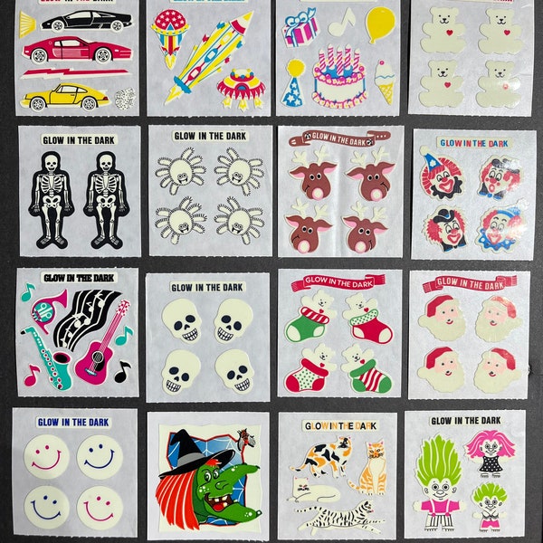 Può includere: Un foglio di adesivi che brillano al buio con vari disegni, tra cui un'auto, un razzo, una torta, un clown, un teschio, una strega e un troll. Gli adesivi sono tutti bianchi con dettagli colorati e il testo "Glow in the Dark" è stampato su ogni adesivo.