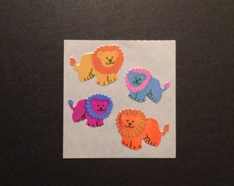 May include: Four colorful lion stickers with a shiny finish. The lions are orange, pink, blue, and yellow.