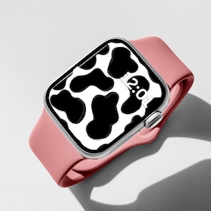 May include: A pink Apple Watch with a white and black cow print watch face. The time displayed on the watch face is 12:01.