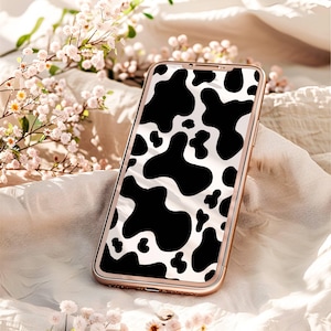 May include: A gold smartphone with a black and white cow print phone case.
