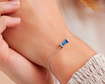 May include: A silver chain bracelet with a blue rectangular gemstone set in a silver frame.
