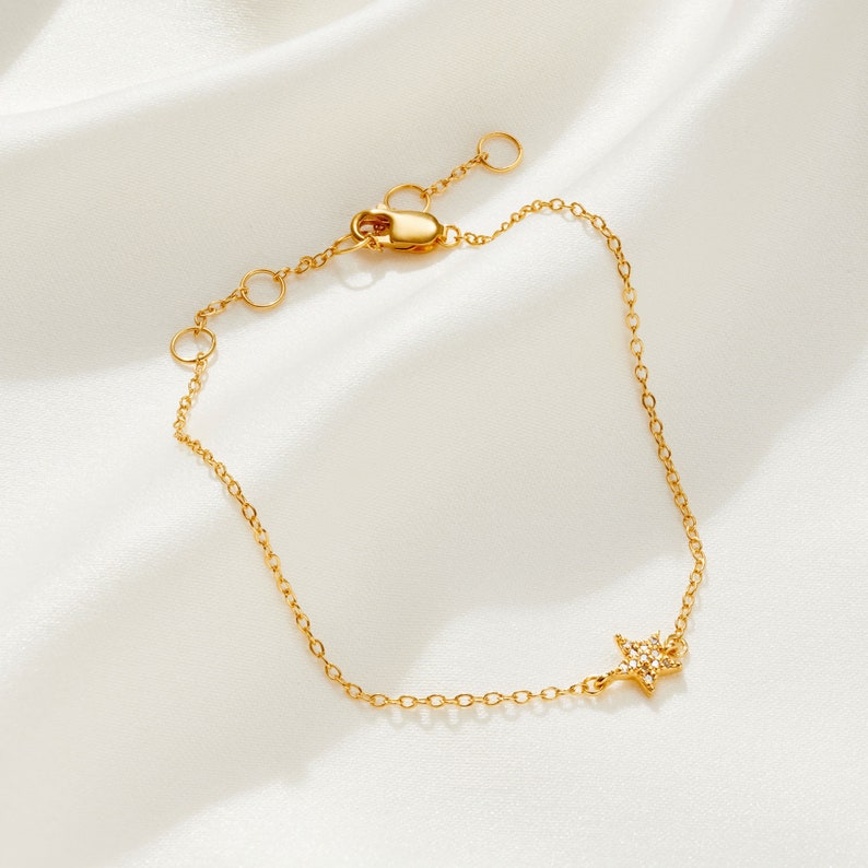 May include: A gold chain bracelet with a small, sparkly star charm.