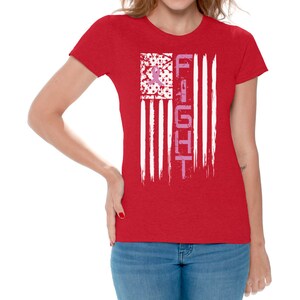 May include: Red t-shirt with a white and pink American flag design. The flag has the word "FIGHT" written vertically down the right side.