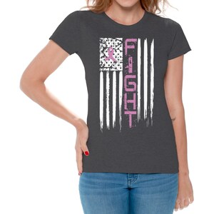May include: A dark heather grey t-shirt with a pink ribbon and the word "FIGHT" printed on a white distressed American flag design.