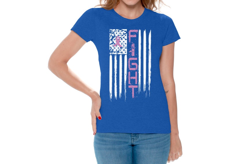 May include: A royal blue t-shirt with a distressed white American flag design. The flag has a pink ribbon in the upper left corner and the word "FIGHT" vertically down the right side.