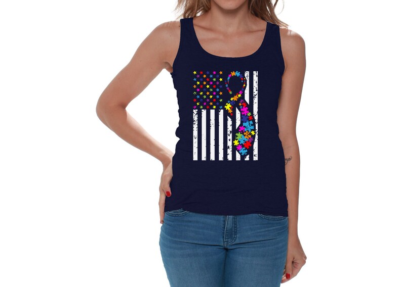 May include: A navy blue tank top with a white distressed American flag design. The flag has a colorful puzzle piece ribbon in the center.