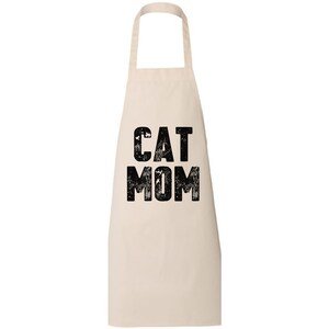 May include: A white cotton apron with black text that reads "CAT MOM" in a distressed font.
