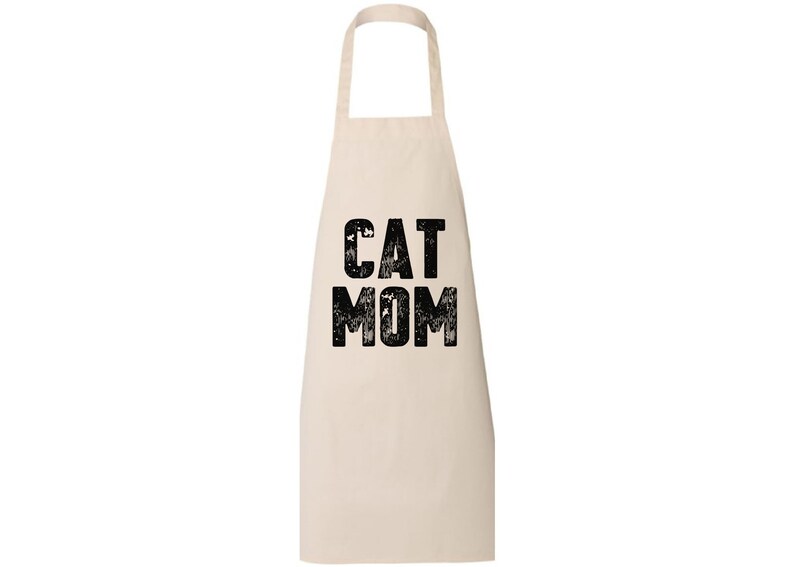 May include: A white cotton apron with black text that reads "CAT MOM" in a distressed font.
