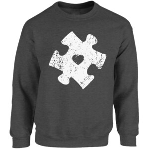 May include: A dark grey sweatshirt with a white distressed jigsaw piece design featuring a small heart in the centre.