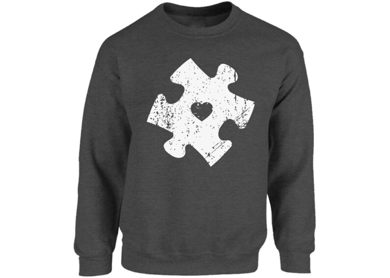 May include: A dark grey sweatshirt with a white distressed jigsaw piece design featuring a small heart in the centre.