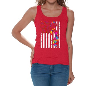 May include: A red tank top with a white American flag design featuring a puzzle piece ribbon. The ribbon is made up of colorful puzzle pieces.