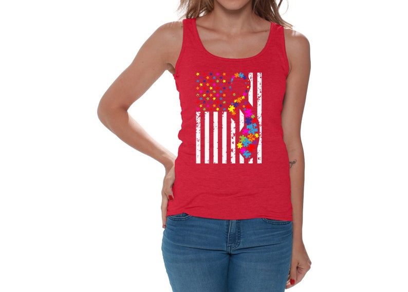 May include: A red tank top with a white American flag design featuring a puzzle piece ribbon. The ribbon is made up of colorful puzzle pieces.