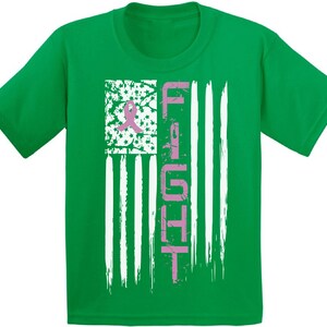 Pu&ograve; includere: Maglietta verde con un nastro rosa e la parola "FIGHT" su un design di bandiera americana rovinato.