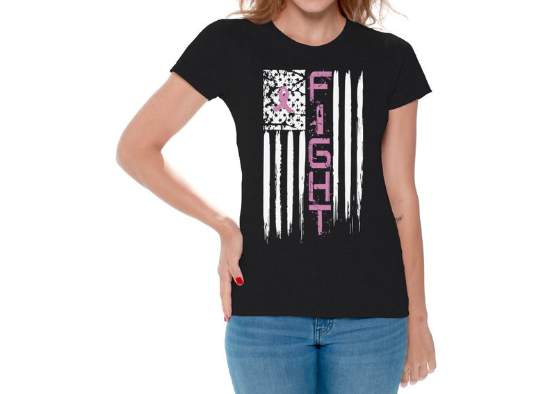 May include: Black t-shirt with a distressed American flag design. The flag is white and black with a pink ribbon in the top left corner. The word "FIGHT" is written vertically down the right side of the flag.
