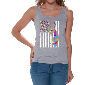 May include: A gray tank top with a white American flag design. The flag has a puzzle piece ribbon in the center, with colors including red, orange, yellow, green, blue, and purple.