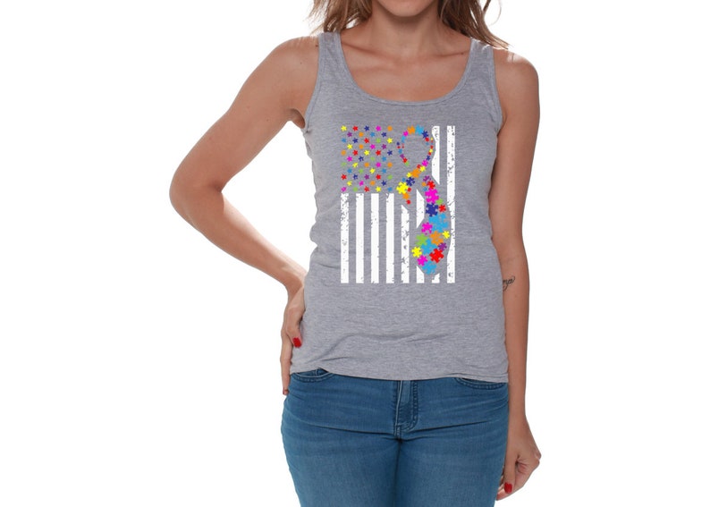 May include: A gray tank top with a white American flag design. The flag has a puzzle piece ribbon in the center, with colors including red, orange, yellow, green, blue, and purple.