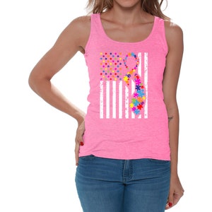 May include: A pink tank top with a white American flag design. The flag has a puzzle piece ribbon in the center, representing autism awareness.