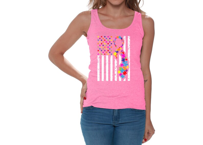 May include: A pink tank top with a white American flag design. The flag has a puzzle piece ribbon in the center, representing autism awareness.