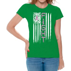 May include: A green t-shirt with a white and pink American flag design. The flag has the word "FIGHT" written vertically in pink on the right side.