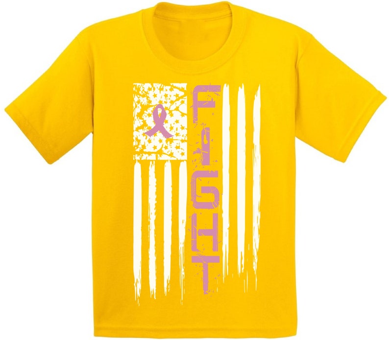 Pu&ograve; includere: Maglietta gialla con un nastro rosa e la parola "FIGHT" stampata su un design di bandiera americana bianca e blu.