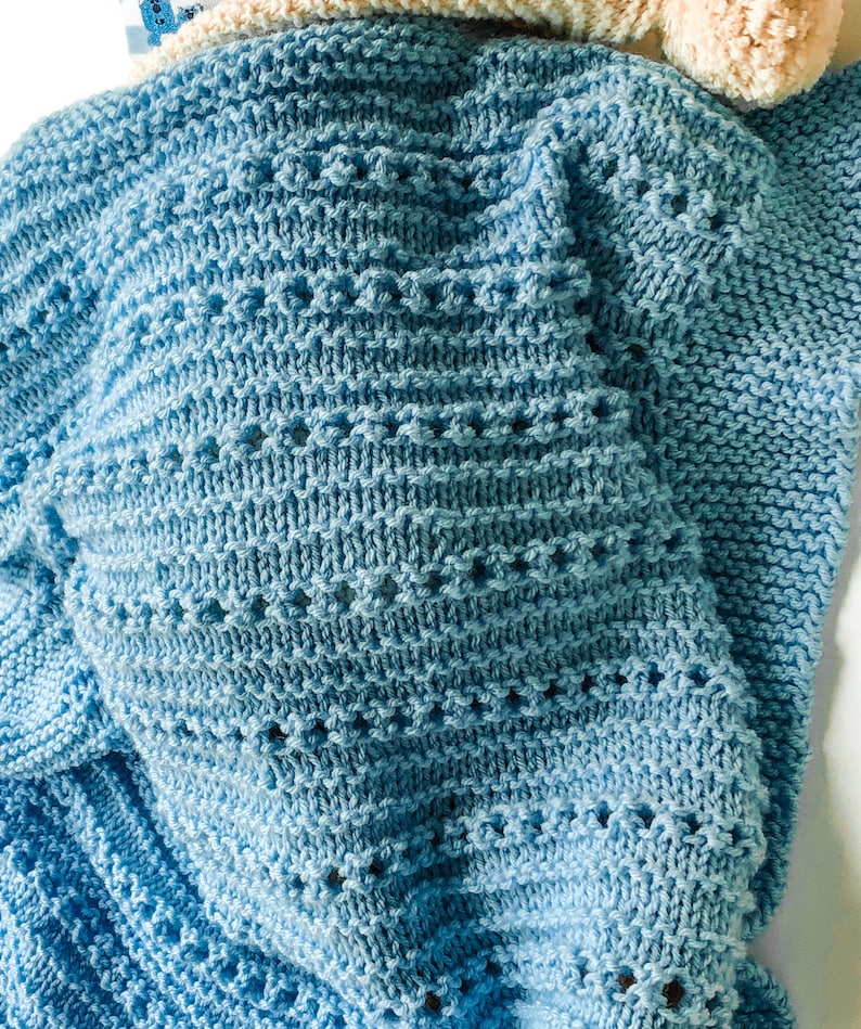 May include: A soft blue knitted baby blanket with a delicate stitch pattern.