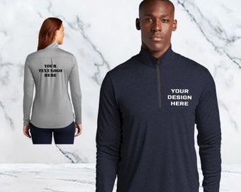 May include: Long-sleeved athletic shirts in navy blue and gray, each with a quarter-zip collar. The navy shirt features the text "YOUR DESIGN HERE" in white, while the gray shirt has "YOUR TEXT/LOGO HERE" on the back. Both shirts are shown on models.