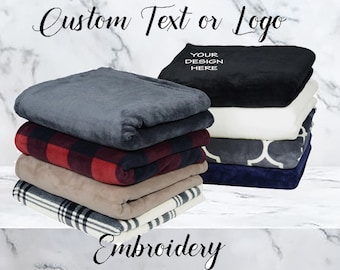 May include: A stack of different colored and patterned fleece blankets. The top blanket is black with the text "Your Design Here" in white. The text "Custom Text or Logo" is at the top of the image. The text "Embroidery" is at the bottom of the image.