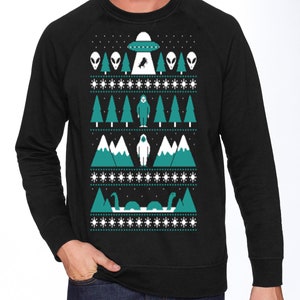 May include: Black sweatshirt with a green and white Christmas sweater design featuring a UFO, aliens, a Bigfoot, and a Loch Ness Monster.