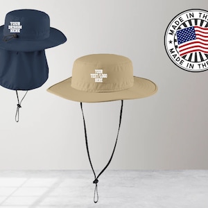 May include: A navy blue sun hat with a neck flap and a tan sun hat, both featuring adjustable chin straps and white text that reads YOUR DESIGN HERE or YOUR TEXT/LOGO HERE. A circular badge with the US flag and text MADE IN THE USA is included.