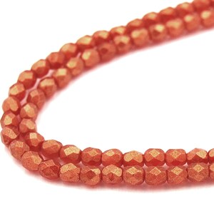 Puede incluir: Una hebra de cuentas de vidrio facetadas de color cobre. Las cuentas son pequeñas y tienen un brillo metálico.