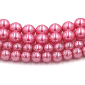 May include: A strand of pink pearl beads. The beads are round and have a smooth, glossy finish.