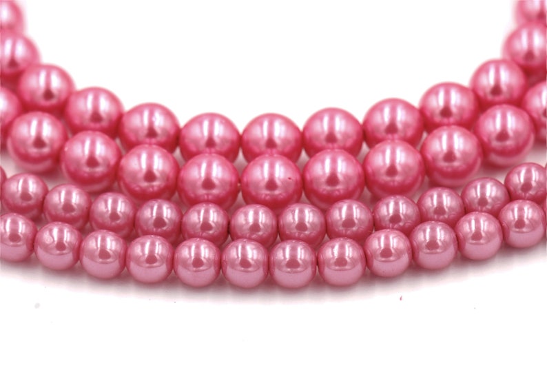 May include: A strand of pink pearl beads. The beads are round and have a smooth, glossy finish.