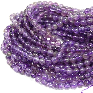 May include: A strand of round, purple amethyst beads. The beads are smooth and polished, and they have a slight sheen.