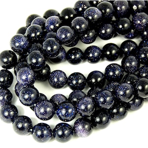 May include: A strand of dark blue gemstone beads with a speckled, starry appearance. The beads are round and smooth, and they are strung together on a clear thread.