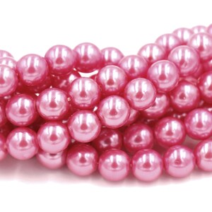May include: A strand of pink pearl beads. The beads are round and have a smooth, glossy finish.