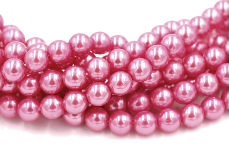 May include: A strand of pink pearl beads. The beads are round and have a smooth, glossy finish.