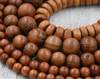 Puede incluir: Primer plano de una hebra de cuentas de madera marrón. Las cuentas son redondas y tienen un patrón de veta de madera natural. Las cuentas están dispuestas en un patrón circular, con algunas cuentas superpuestas.